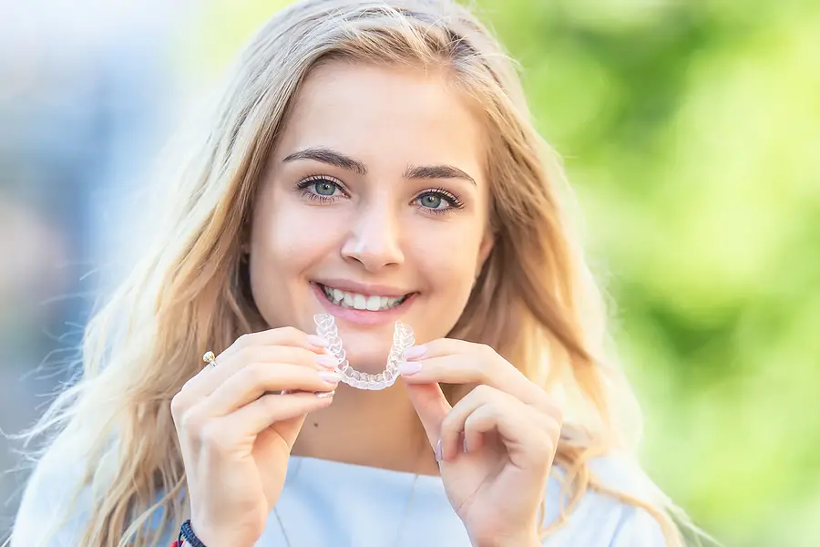 woman smiling holding invisalign