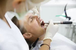 man in dentist chair with mouth open and dentist working