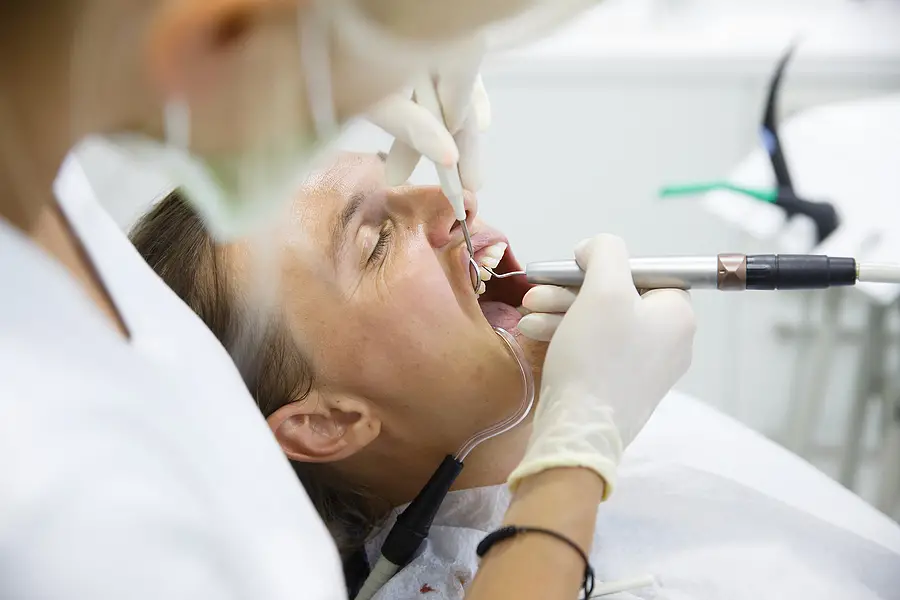 man in dentist chair with mouth open and dentist working