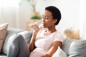 woman drinking water on sofa