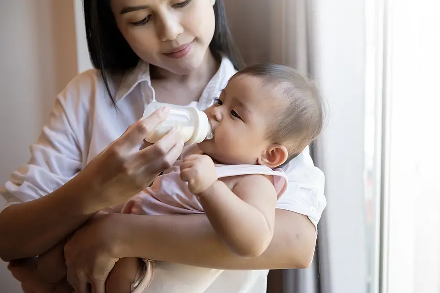 woman holding baby drinking from bottle