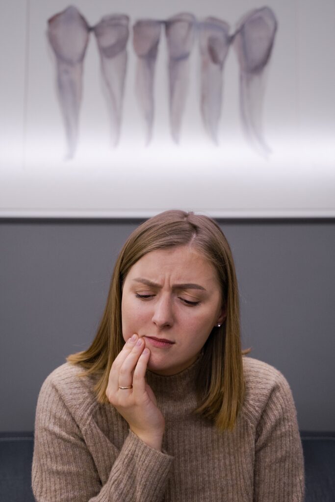 woman holding cheek in pain with mouth xray in background