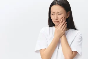 woman holding her cheek in pain