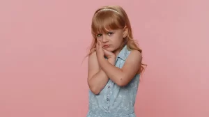 young girl holding hands by mouth showing pain